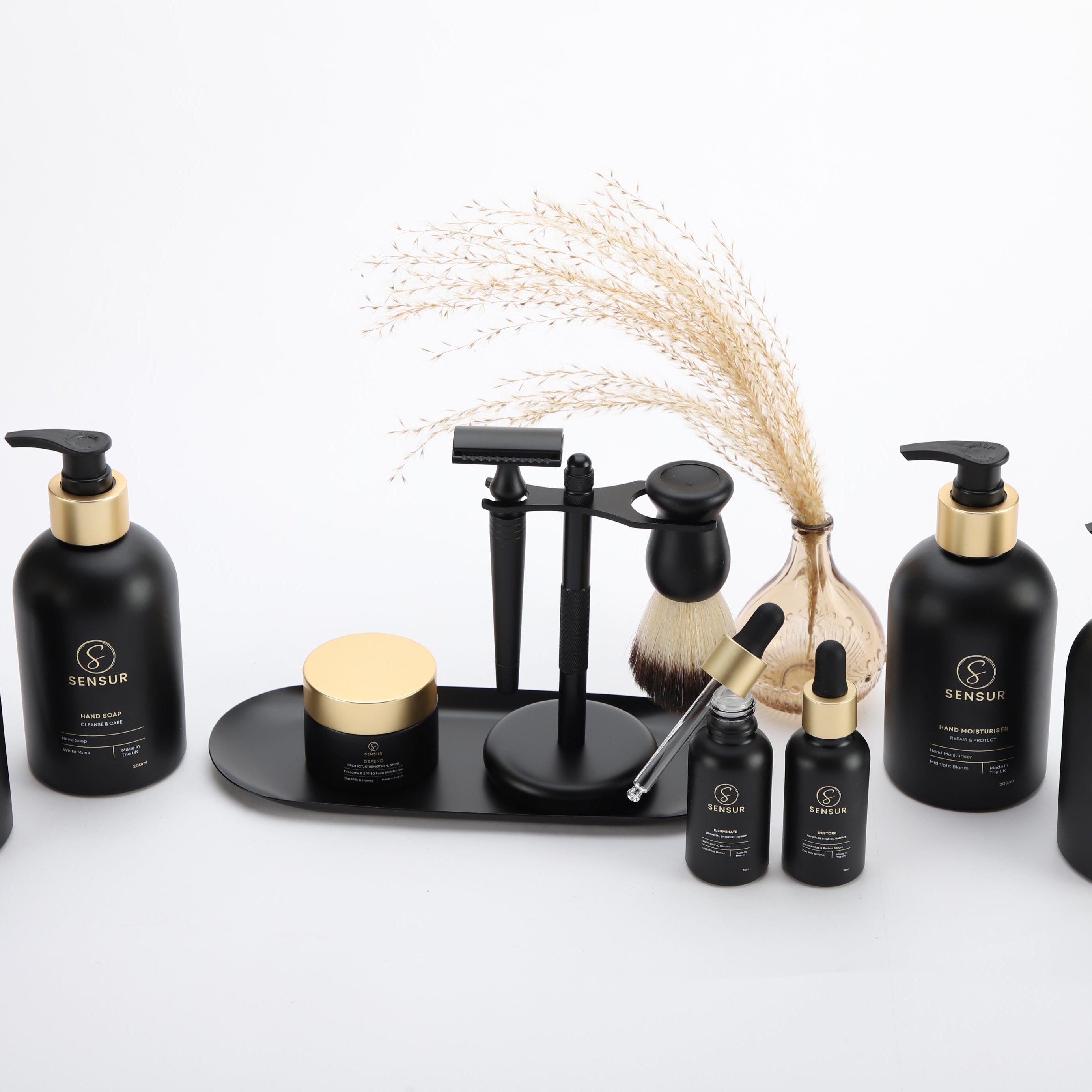 Set of black grooming products with gold accents on a white background