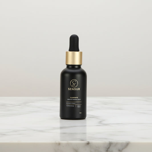 Black dropper bottle with gold cap on a marble surface against a dark background